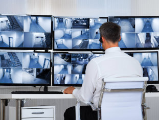 adult man monitoring security cameras